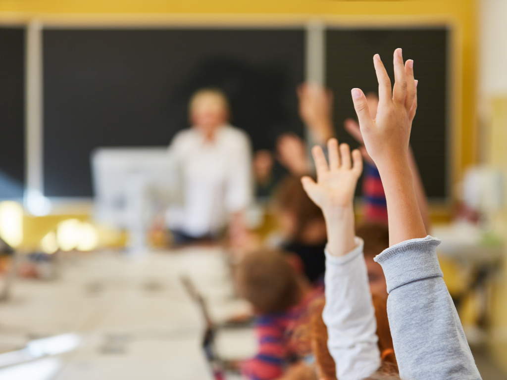 Children rising hands in classroom
